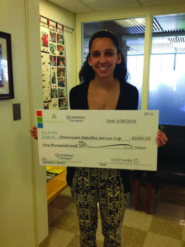 Senior Lindsey Banks holds the $1,000 check for the QU301 Dominican Republic service trip. The money will be used to build a cafeteria in the neighborhood where students volunteer during their time abroad.